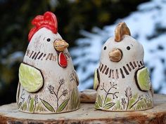 two ceramic chickens sitting on top of a tree stump