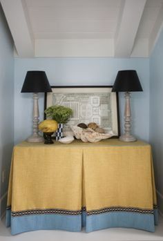 a table with two lamps on top of it next to a painting and vases