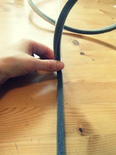 a hand is holding the edge of a piece of metal on top of a wooden table