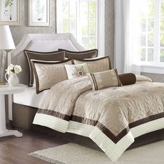 the comforter is made up with brown and white bedding, along with matching pillows