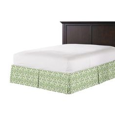 a bed with a green and white bedspread on it's headboard