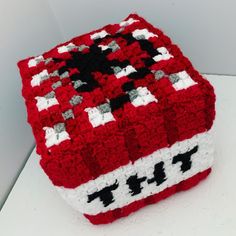 a red and white crocheted box sitting on top of a table