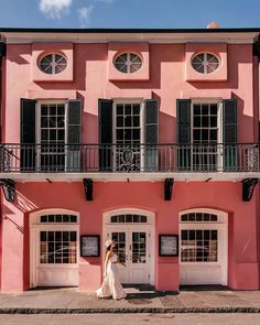 a woman standing in front of a pink building