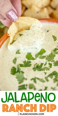 a hand dipping tortilla chips into a bowl of ranch dip with cilantro