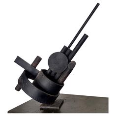 a metal sculpture with two sticks sticking out of it's center and an object in the background