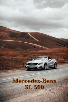 a car driving down the road in front of a hill and cloudy sky with words mercedes - benz sl 50