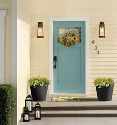 a blue front door with two white planters on the steps