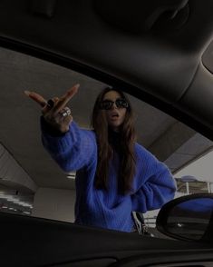 a woman wearing sunglasses is standing in the back seat of a car with her hand up