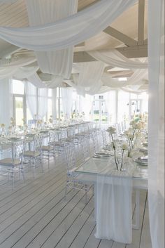 a room filled with lots of tables covered in white draping and flower centerpieces