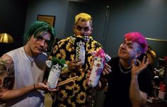 three men are dressed up as clowns and holding candy