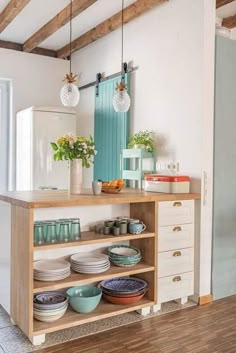 a kitchen area with plates and bowls on a wooden counter top next to a refrigerator