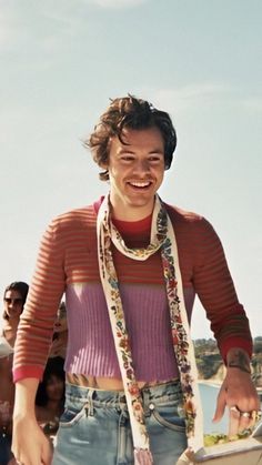 a young man is smiling while holding a frisbee in one hand and wearing a scarf around his neck