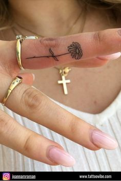 a woman's hand with a cross tattoo on it