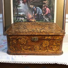 an old wooden box with pictures on the front and sides, sitting on a table