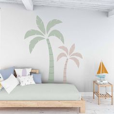 a bedroom with a palm tree decal on the wall next to a bed and side table