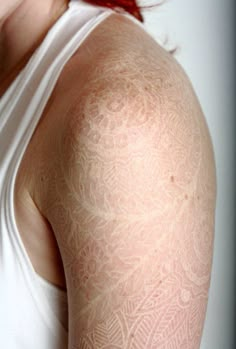 the back of a woman's arm with white tattoos on it and red hair