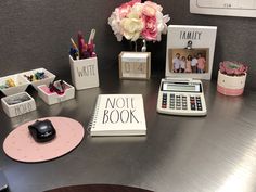 an office desk with various personal items on it and a note book next to the calculator