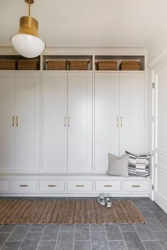 a room with white cabinets and gray tile flooring next to a rug on the floor