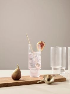 a wooden tray topped with glasses and figs next to a cup filled with water