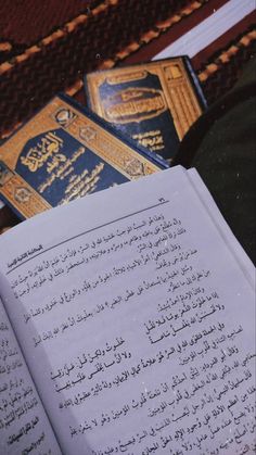 an open book sitting on top of a table next to another book with arabic writing