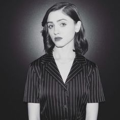 a black and white photo of a woman in pinstripe shirt looking at the camera