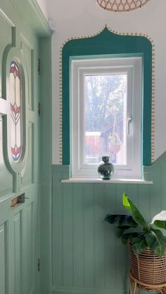 a bathroom with green painted walls and a potted plant in the window sill