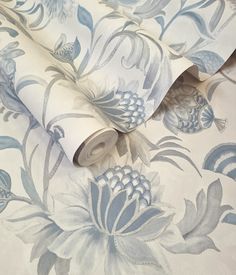 a blue and white wallpaper with large flowers on it's side, next to a roll of toilet paper