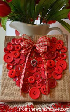 a red heart shaped card with buttons attached to it and a bow on the front