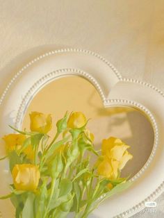 some yellow flowers are in a heart shaped vase