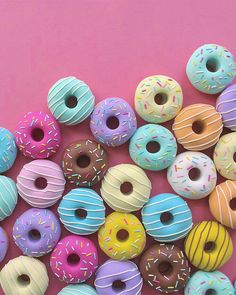 there are many donuts with sprinkles all over the place on this pink background