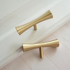 two brass handles on a white wall