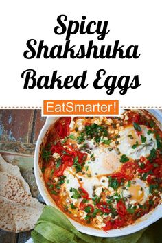 an egg dish in a white bowl with spinach leaves on the side and text spicy shakshuka baked eggs