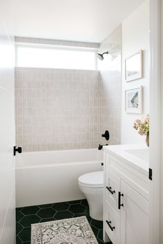 a white toilet sitting next to a bath tub in a bathroom with black and white flooring