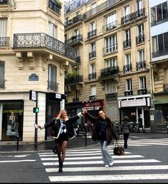 two women crossing the street in front of buildings