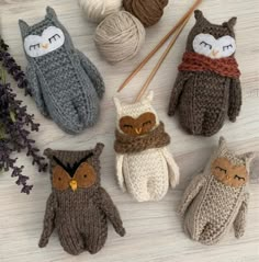 four knitted owl mittens sitting on top of a table next to yarn balls