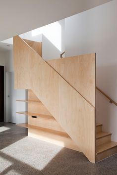 a wooden stair case next to a window in a room with carpeted flooring