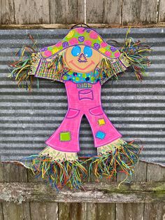 a paper doll hanging on the side of a wooden fence