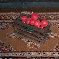 a wooden crate filled with red apples on top of a rug