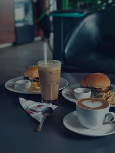 two plates with sandwiches, french fries and a cup of coffee are on the table