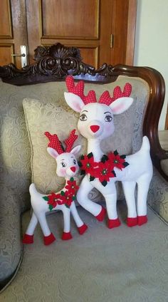 two reindeer figurines sitting on top of a couch next to another deer statue