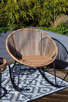 two wicker chairs sitting on top of a wooden deck next to a planter