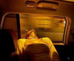 a woman laying down in the back seat of a car next to a window on a train