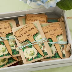 small wooden tags in a box tied with twine and flowers on green tablecloth