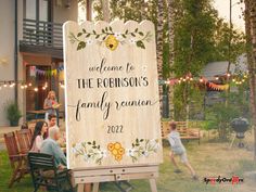 a family reunion sign in front of a house with people sitting at tables and chairs around it