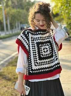 a woman in a black and white sweater is walking down the street with her hand on her head