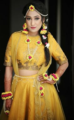 a woman in a yellow lehenga with flowers on her head and necklaces around her neck