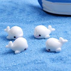 three little white whale figurines sitting on blue carpet