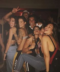 a group of young people standing next to each other at a bar with drinks in their hands