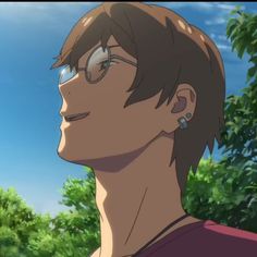 a young man with glasses staring at something in the distance while standing next to trees