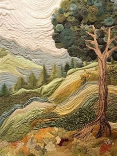 a quilted wall hanging with a tree and mountains in the background